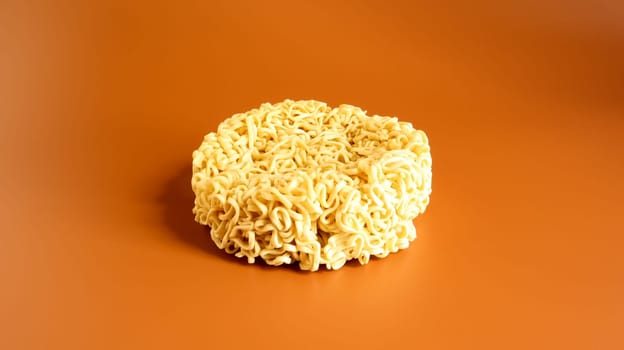 Korean instant noodles in the shape of a circle on a brown background. A yellowish-white dried raw vermicelli with long round lines and twisted in different directions into a briquette