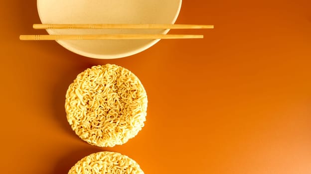 dry instant noodles in a typical circle shape on a plate with chopsticks. The effect of instant noodles on human health. pasta, for the preparation of which it is enough to pour boiling water.