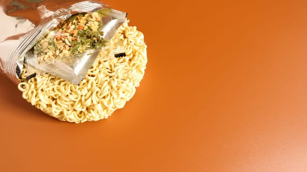 Raw instant food noodles from an unnamed foil packaging without a name close-up with spices and butter. pasta, for the preparation of which it is enough to pour water. Copy space.