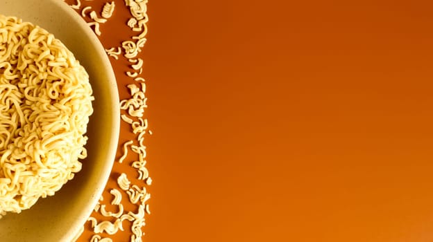 Raw dry instant noodles in a deep ceramic beige soup bowl on a brown background. pasta, for the preparation of which it is enough to pour boiling water and wait a few minutes. Copy space.