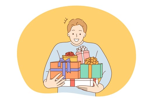 Anniversary, Birthday or Christmas present, celebration concept. Young happy man man carrying heap of birthday gifts in boxes with festive ribbons. Surprise, anniversary, gift, happiness