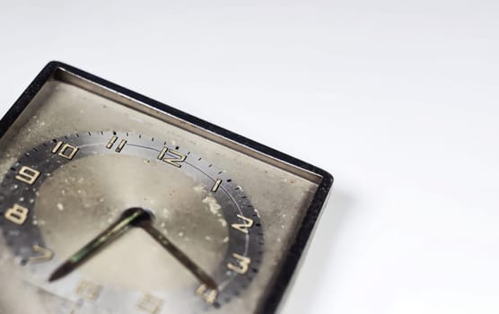 Old worn clock with square dial isolated on a white background. Analog time measurement. Vintage and retro object. Copy space.