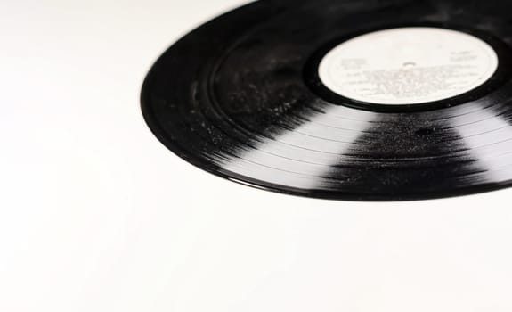 an old and dusty black vinyl record isolated on a white background. Equipment for listening to music. Vintage object