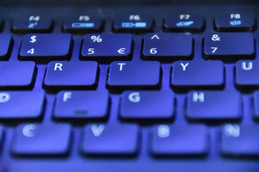 A laptop keyboard with blue light shining on it