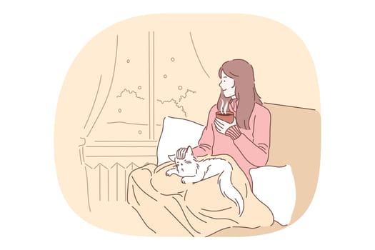 Comfort, rest, cozy relaxation with cat and hot tea in bed at home concept. Young smiling girl drinking tea or coffee in bed, petting cat and relaxing looking at window at home