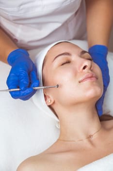 Beautician using professional multiple hole spoon to clean cleansing face and pores