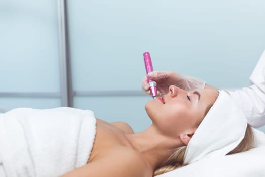Woman having facial treatment in beauty salon, closeup. Oxy derma therapy with derma pen. Side view