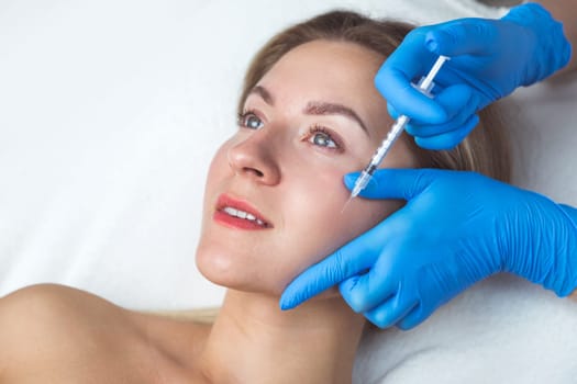 Rejuvenating facial injections procedure for tightening and smoothing wrinkles on the face skin of a beautiful, young woman in a beauty salon.Cosmetology skin care.