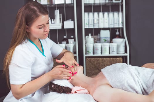 Girl masseur makes facial massage for a young lady in the beautician's office