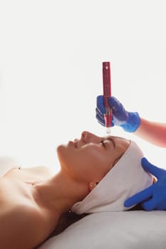 Professional cosmetology. Beautician is using dermapen on woman face skin, side view. Skin beauty and health.