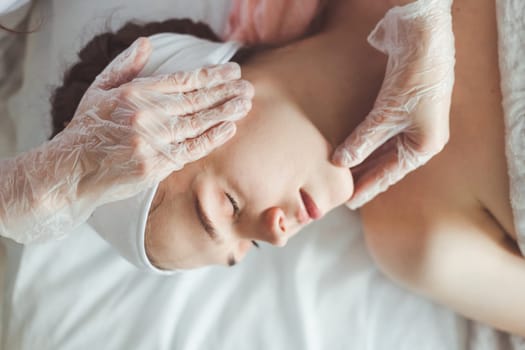 Doctor examining young woman face before cosmetic procedures