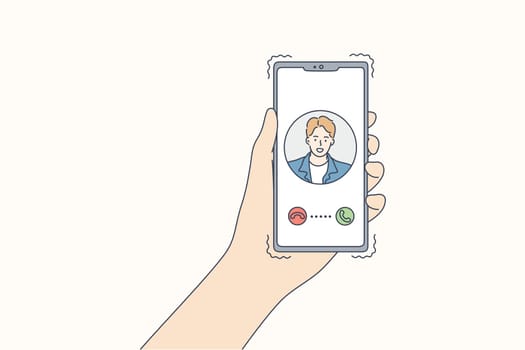 Technology, communication, calling, online concept. Human hands hold smartphone with incoming video call of young man boy. Remote chatting in social media network application on coronavirus lockdown.