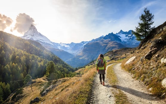 Young woman walking along a trail in the mountains near Swiss resort town of Zermatt