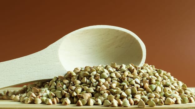 Buckwheat scattered background, raw green cereal in a wooden spoon. Healthy groats. Organic raw non-fried vegetarian food. The concept of a healthy and balanced diet. Diet product. healthy groats.