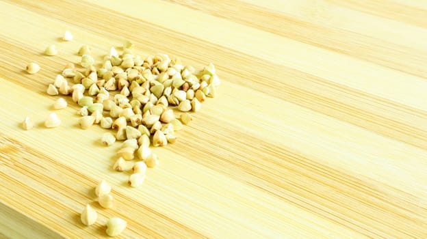 Green buckwheat seeds on a wooden background. Great food. healthy groats. Organic raw non-fried vegetarian food. The concept of a healthy, balanced and dietary diet. Copy space