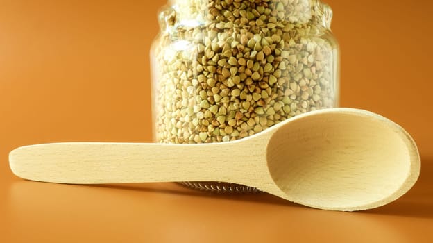 Green sprouts of raw organic buckwheat in a glass cereal jar with a wooden spoon. Vegan food concept. Organic food. The concept of diet, weight loss, healthy and proper nutrition. Copy space for text