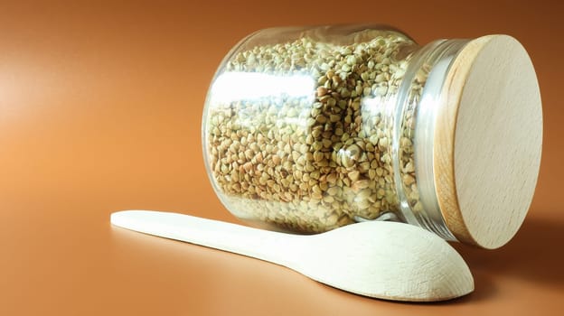 Green sprouts of raw organic buckwheat in a glass cereal jar with a wooden spoon. Vegan food concept. Organic food. The concept of diet, weight loss, healthy and proper nutrition. Copy space for text