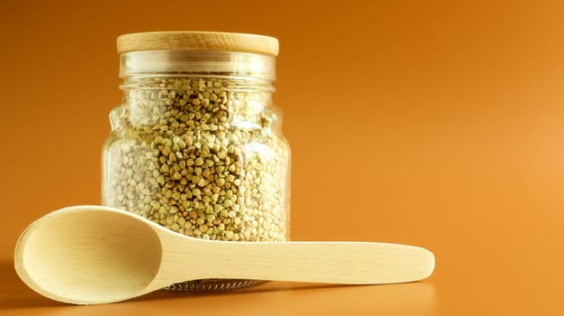 Green sprouts of raw organic buckwheat in a glass cereal jar with a wooden spoon. Vegan food concept. Organic food. The concept of diet, weight loss, healthy and proper nutrition. Copy space for text