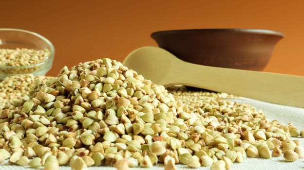 Raw green organic buckwheat in plates and lies in a scattered pile on a table in the kitchen. Diet food. Copy space. The concept of vegetarianism, balanced and healthy nutrition