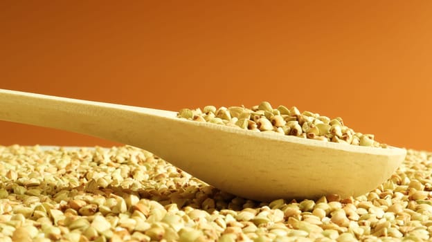 Buckwheat scattered background, raw green cereal in a wooden spoon. Healthy groats. Organic raw non-fried vegetarian food. The concept of a healthy and balanced diet. Diet product. healthy groats