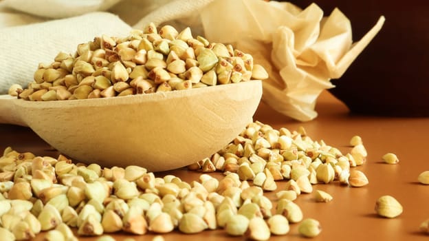 Buckwheat scattered background, raw green cereal in a wooden spoon. Healthy groats. Organic raw non-fried vegetarian food. The concept of a healthy and balanced diet. Diet product. healthy groats