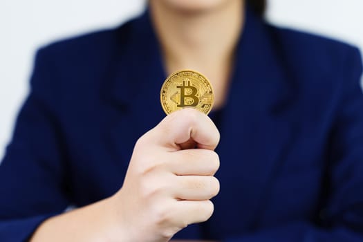 Close up of businesswoman holding some pieces of golden Bitcoin token , Bitcoin is one of the popular cryptocurrency