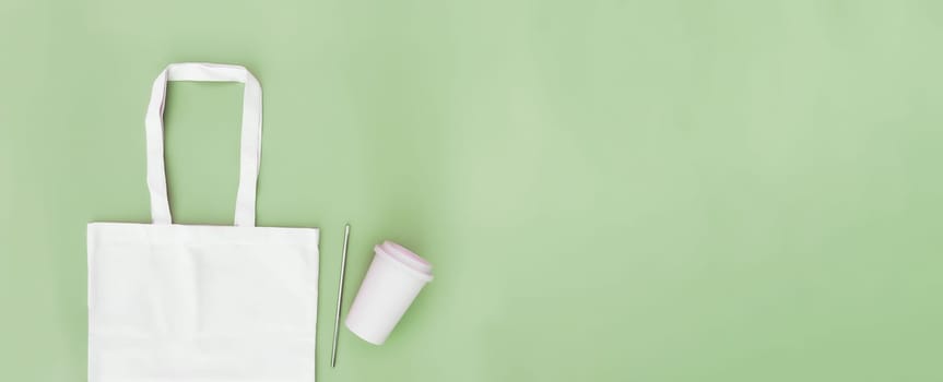 Eco white craft paper bag, metal drink straw, coffee cup on green background flat lay with copy space empty advertising area. Banner mock up for delivery service, sustainable resources concept