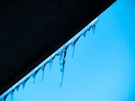 A frozen icicle of ice against a blue sky. Winter. Background image. Place for text.