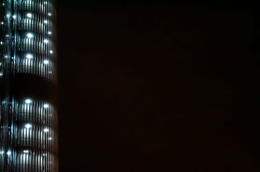 Night illumination of a tall business building. Background image. Place for text. City life.
