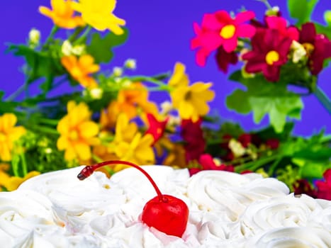 Red cherry from marmalade on white creamy flowers of a biscuit cake. Food photo. Dessert. Cake baking. Place for text. Shop window. Poster. Promotional event. Cake recipe.