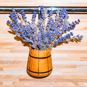 Decorative bouquet of forest violets in a wooden vase on the wall. Background image. Place for text. Decor and decoration.