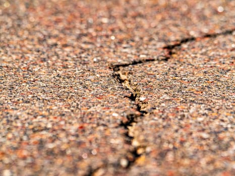 Closeup of a longitudinal crack in the asphalt pavement of a highway. Place for text. Background image. Texture.
