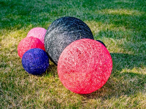 Colored balls of wound thread on a grassy lawn. Design. Background image. Place for text. Interior.
