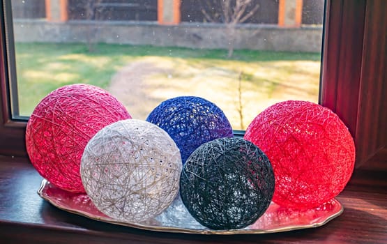 Colored balls of wound thread on a windowsill. Design. Background image. Place for text. Interior.