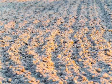 Plowed land on a farm field under the sun's rays. Agriculture. Background image. Place for text. Spring sowing.