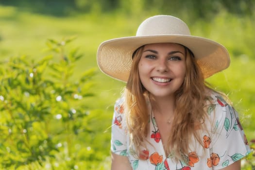 Smiling attractive  young woman wearing straw hat is posing outdoors. Horizontally.
