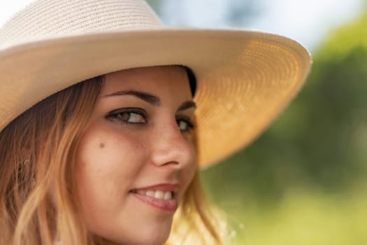 Closeup view  of face of the attractive young woman  wearing  straw hat. Horizontally.