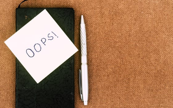 OOPS! Written on sticky notes. Mistake Learning, wrong, blooper, error regret sayings background. Fault, defect, careless lesson correction and reconciliation thought concept. Table top view. Flat Lay
