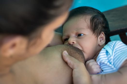 Latin infant breastfeeding directly from her mother's breasts