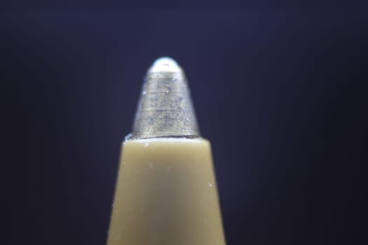 Macro photo of ballpoint pen tip with dark grey background. Extreme macro image of metal ballpoint pen on grey background.