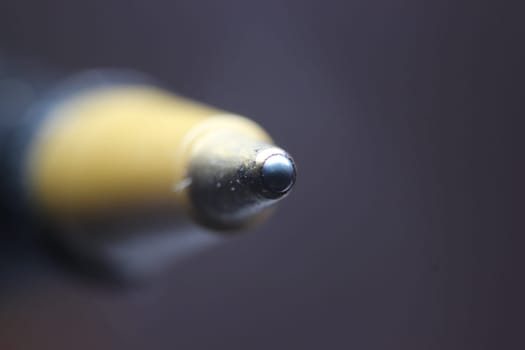 Macro photo of ballpoint pen tip with dark grey background. Extreme macro image of metal ballpoint pen on grey background.