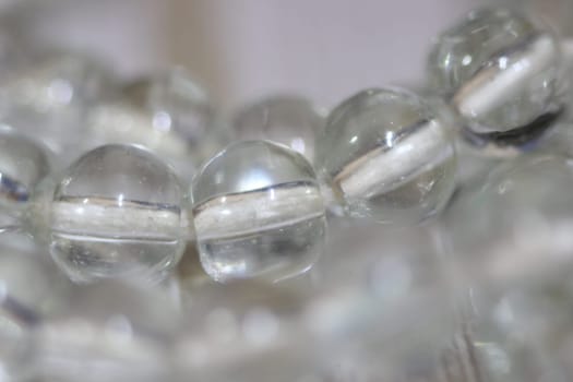 Macro photograph with selective focus of glass shiny prayer beads or rosary with copy space for text. Religion concept of ramadan or Eid for muslims.