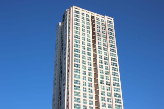 The wide-angle view of a skyscraper commercial building with blue sky on sunny day.