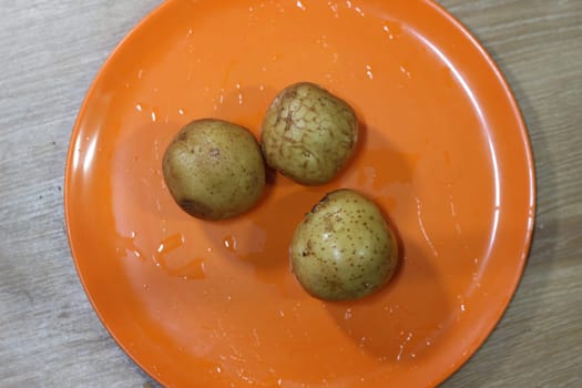 Potato on a orange color cutting board.