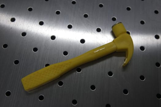 Selective focused, closeup view of toy hammer made from plastic placed on metal background