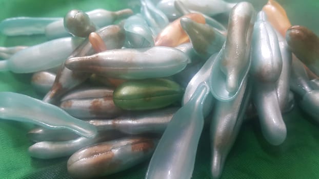 Colorful shiny bright oil capsule spread over a green background. Olden opaque oil capsules.
