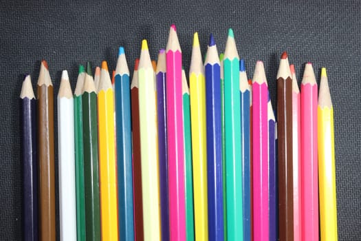 Close-up view of bright colored multicolor pencils on black background