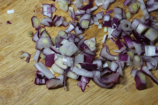 Chopped white onion with sharp knife on wooden cutting board. High angle top view of chopped onions pieces