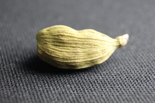 Closeup top view of dried green Elettaria cardamomum fruits with seeds, cardamom spice scattered on white background