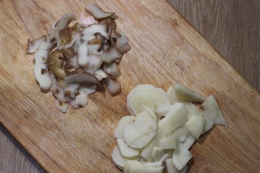 Chopped potato slices with peelings on a wooden cutting board
